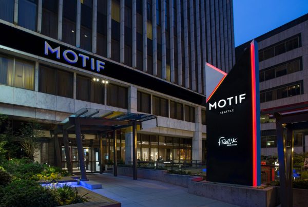 Exterior view of the Motif Seattle hotel entrance, featuring modern architecture and illuminated signage during evening.