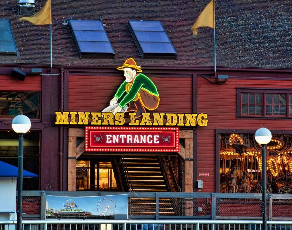 The entrance of Miners Landing features a large sign with a neon miner figure.