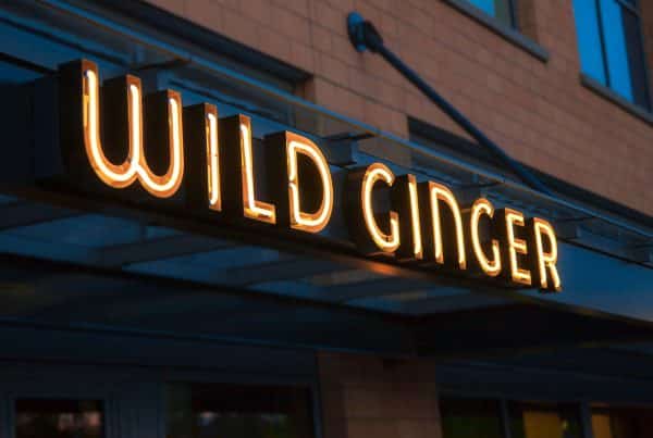 Neon sign reading "Wild Ginger" on the exterior of a brick building.
