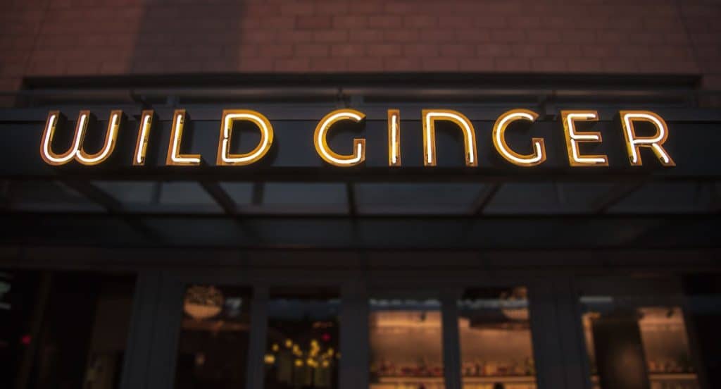 Neon sign reads "Wild Ginger" on a storefront at night.