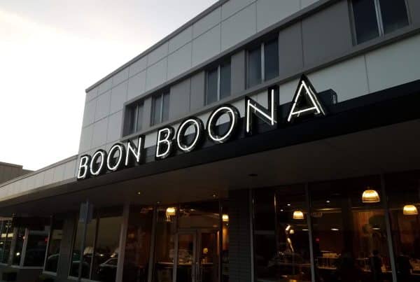 Exterior view of Boon Boona coffee shop with illuminated sign and large windows.