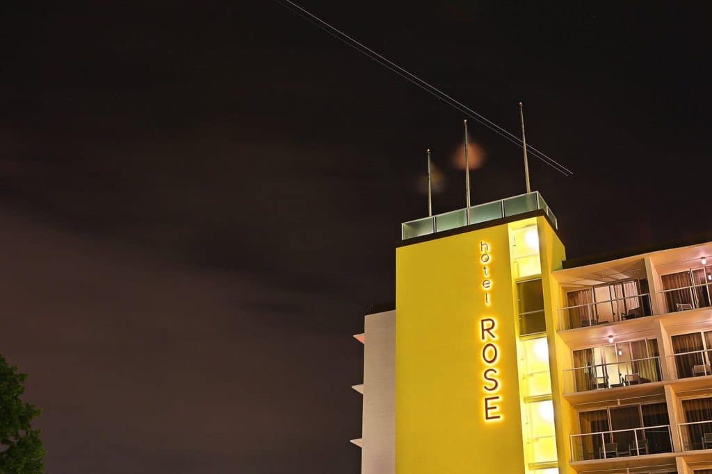 Night view of the Hotel Rose building with illuminated exterior signage against a dark sky. Night view of the Hotel Rose building with illuminated exterior signage against a dark sky.