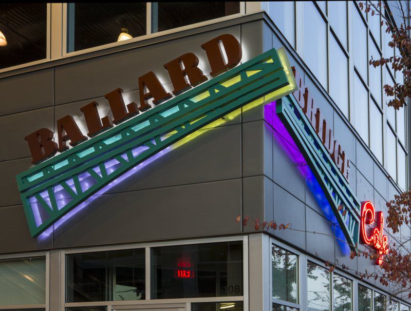 Exterior of a building with a "Ballard" sign in large letters and colorful neon accents.