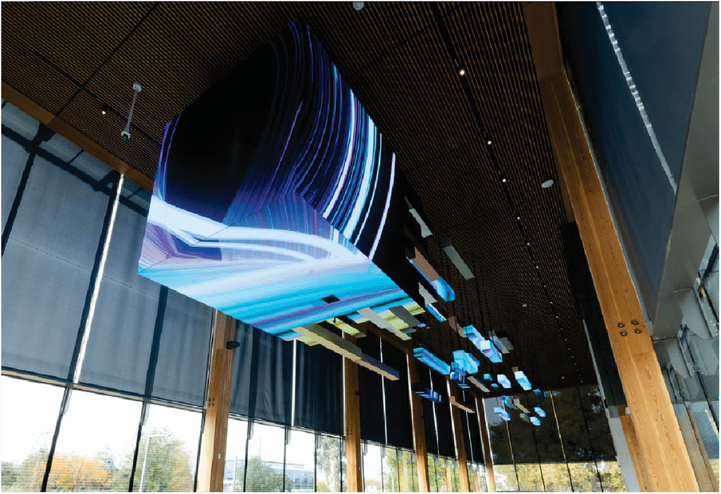 Ceiling installation with abstract LED digital art and wood panel accents in a modern building's interior.