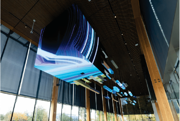 Ceiling installation with abstract LED digital art and wood panel accents in a modern building's interior.