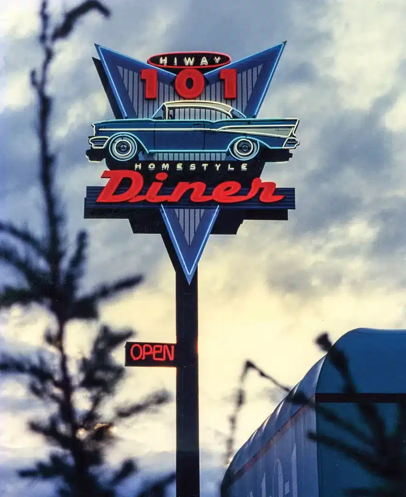 Retro diner sign reading "Hiway 101 Homestyle Diner" with an illustration of a classic car and a neon "Open" sign.