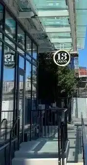 Exterior view of a building with a glass entrance featuring a "13 Coins" sign.