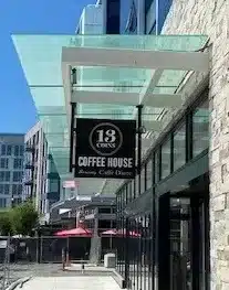 Exterior of a building with a sign reading "13 Coins Coffee House, Bakery, Café, Desserts" under a glass awning.