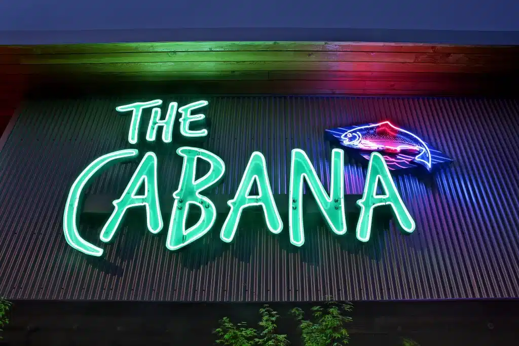 A neon sign reading "The Cabana," reminiscent of Seattle's Neon, features a fish design on a dark wooden wall.