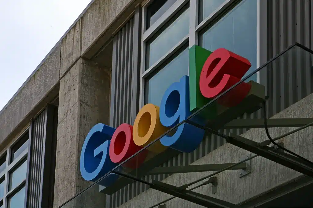 Close-up of the Google logo on the side of a modern building. The letters are in blue, red, yellow, and green colors.