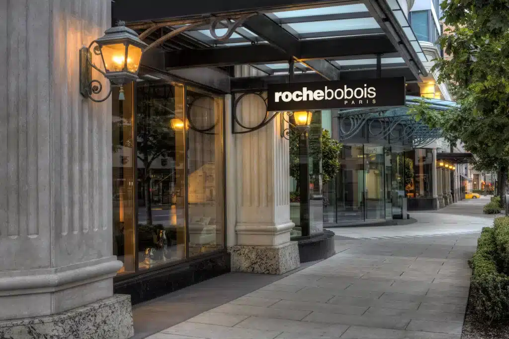 Street view of a Roche Bobois store with large windows and ornate street lamps, showcasing a modern architectural design.