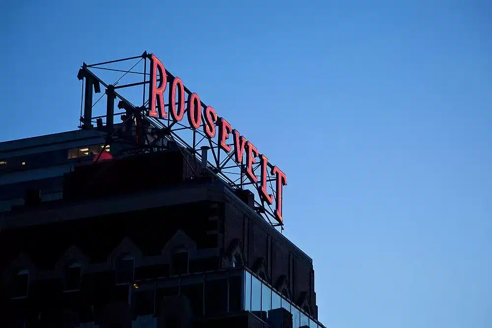 Sign on rooftop reads "Roosevelt" in red letters against a clear blue sky.